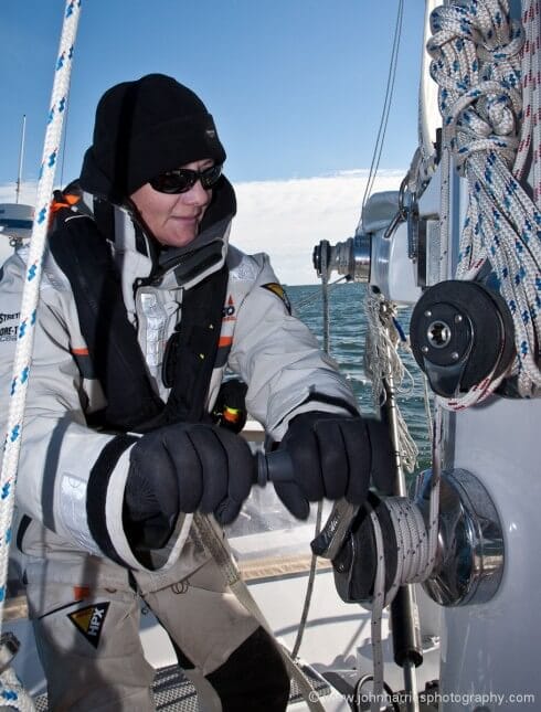 Phyllis grinds the mail halyard tight, and then grinds the last few inches of the pennant in. When I said you need powerful winches for this, I was not kidding. Remember it is now blowing 20 knots true and the sail is fully loaded. Also, when you come to shake out the reef, which we do simply by reversing this procedure, you will need the powerful winch once again.