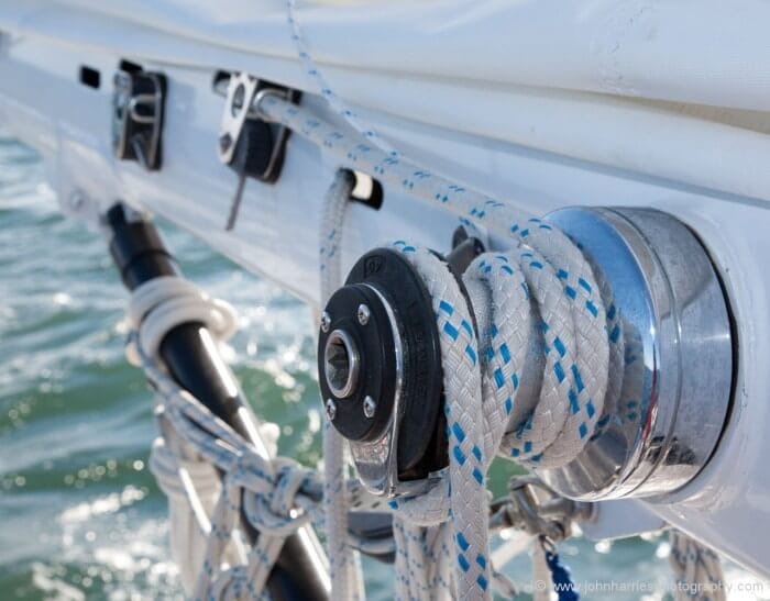 Phyllis has unloaded the first reef from the winch using a clutch and in this photo has loaded up the second reef onto the winch so we are ready to go if the wind pipes up some more. Note that the reefing lines are all different colours and rope types so that it is easy for us to tell them apart. Phyllis adjusts the vang and eases the main sheet back out and we are done. If we are expecting really heavy weather, we put a safety strop through the cringle to take the load if the pennant breaks, and tie the bunt down with sail ties through the reef points and between the boom and the sail. But normally, the bunt just rests in the lazy jacks. And it took you more time to read this than it takes us to do it. I have timed myself at less than three minutes, soup to nuts.