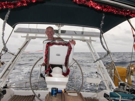 Man at helm of sailboat decorated for Christmas