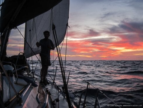 Man on sidedeck of sailboat underway offshore in the evening Pelerin more trhan proved her capability - checking the sail trim as night falls 145 IMG_5953