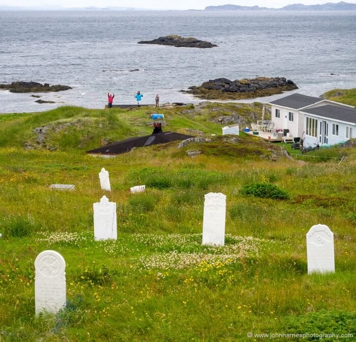 A young family flies a kite framed by the graves of their ancestors.